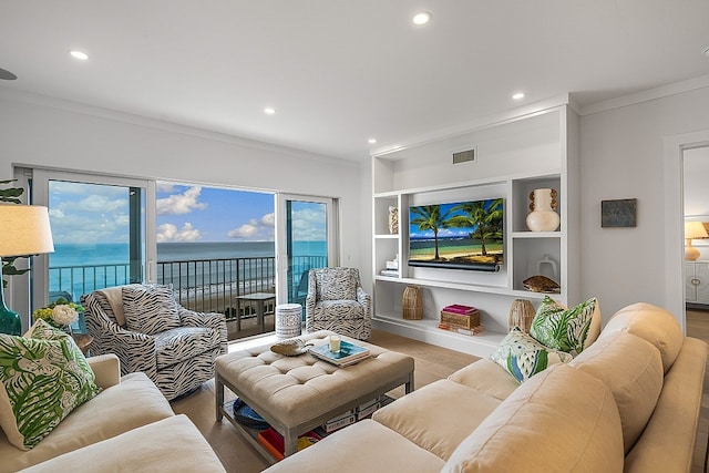 living room featuring wood-type flooring, a healthy amount of sunlight, a water view, and crown molding