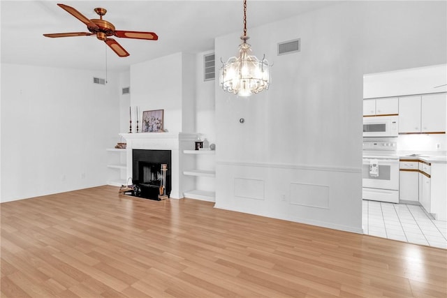 737 Timber Ridge Trl SW Unit B, Vero Beach, FL 32962 - unfurnished living room featuring a chandelier, light wood-style flooring, ceiling fan, a high ceiling, and a fireplace