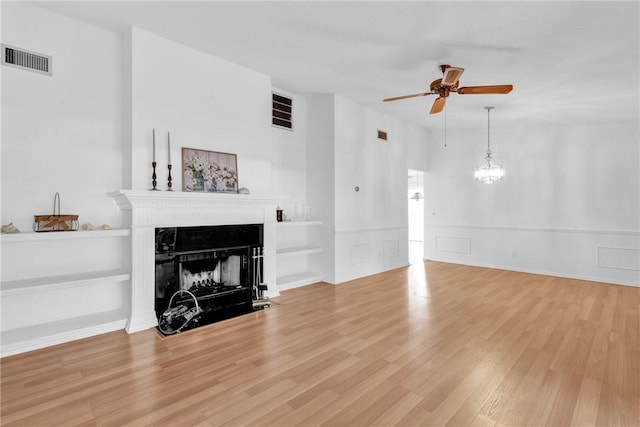 737 Timber Ridge Trl SW Unit B, Vero Beach, FL 32962 - living area featuring a ceiling fan, a fireplace with flush hearth, wood finished floors, a chandelier, and a wainscoted wall