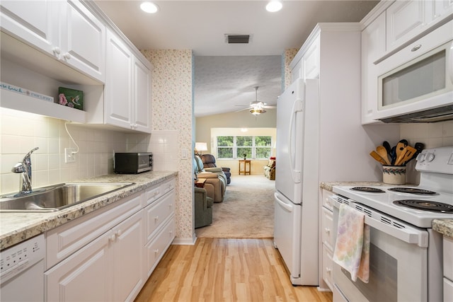 kitchen with white cabinetry, white appliances, vaulted ceiling, and a sink