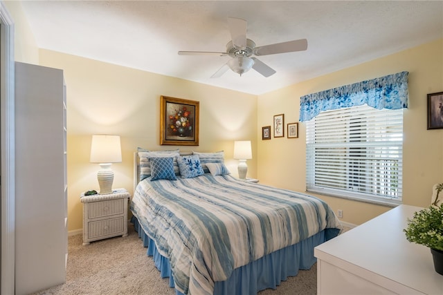 bedroom with light carpet, baseboards, and a ceiling fan