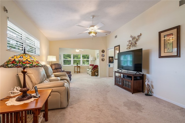 carpeted living area with visible vents, lofted ceiling, baseboards, and a ceiling fan