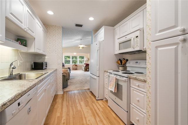 kitchen featuring white appliances, visible vents, a sink, white cabinetry, and open floor plan