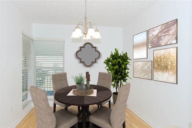 dining area featuring an inviting chandelier, light wood-style floors, and baseboards