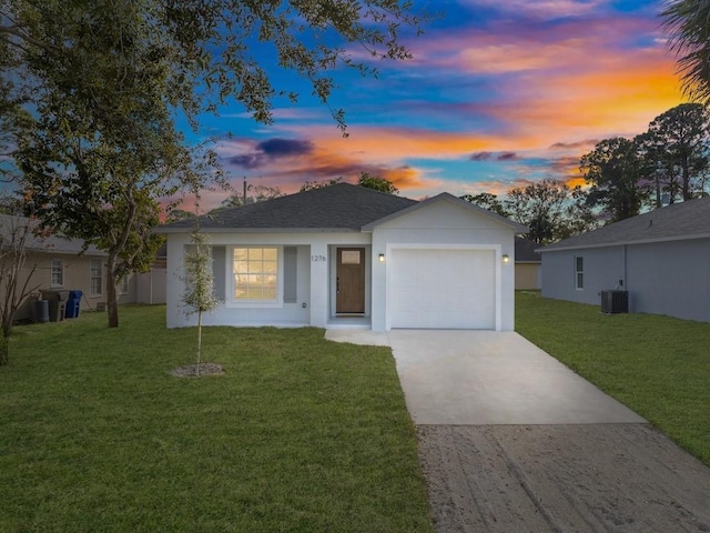 ranch-style house with a yard, a garage, and central AC unit