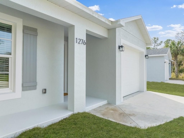 view of exterior entry featuring a garage and a lawn