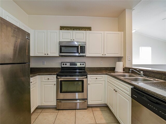 kitchen with light tile patterned floors, appliances with stainless steel finishes, sink, and white cabinets