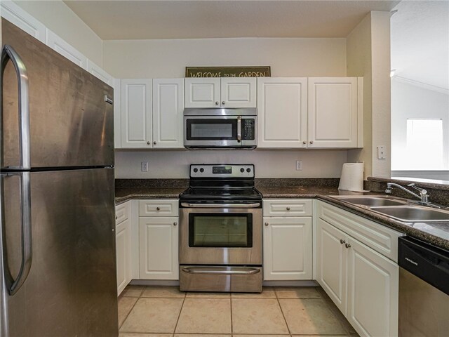 kitchen with appliances with stainless steel finishes, sink, light tile patterned floors, and white cabinets