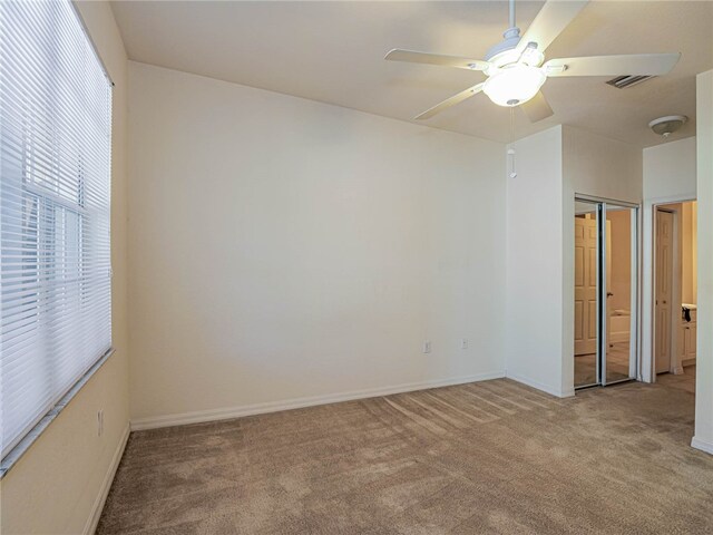 empty room featuring ceiling fan and light colored carpet