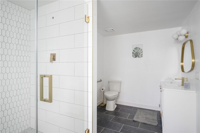 bathroom featuring toilet, a shower with shower door, and vanity