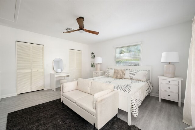 bedroom with ceiling fan, multiple closets, and hardwood / wood-style floors