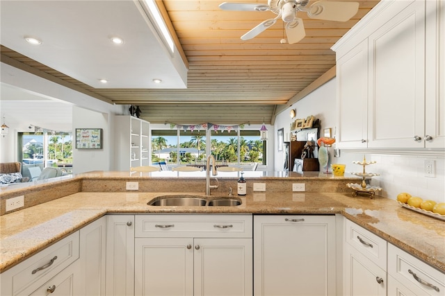 kitchen with white cabinetry, sink, ceiling fan, light stone countertops, and tasteful backsplash