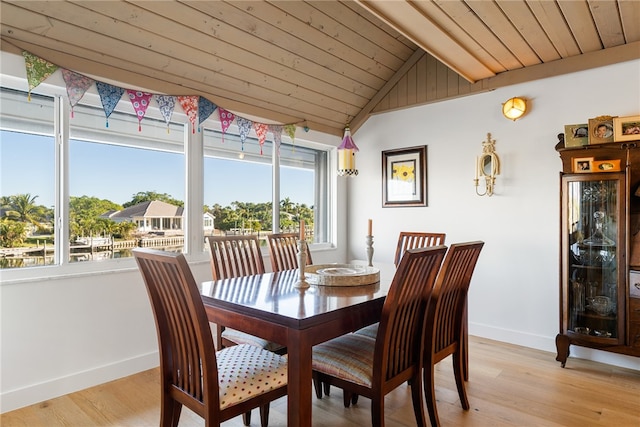 dining room with lofted ceiling with beams, light hardwood / wood-style floors, and wooden ceiling