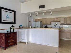 kitchen with freestanding refrigerator, light countertops, light tile patterned flooring, and white microwave