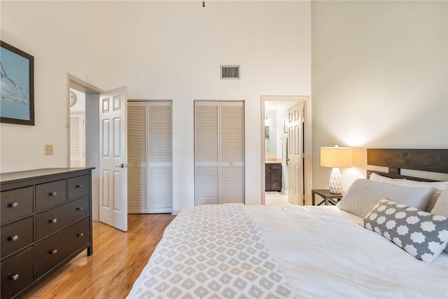 1155 Winding Oaks Cir E Unit 104, Vero Beach, FL 32963 - bedroom with connected bathroom, visible vents, light wood finished floors, a towering ceiling, and two closets