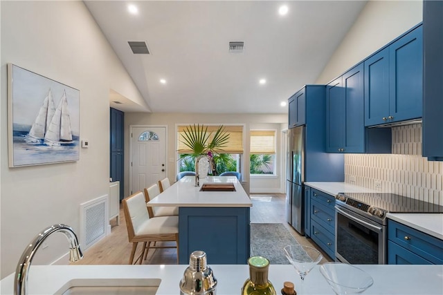 kitchen featuring vaulted ceiling, appliances with stainless steel finishes, sink, a breakfast bar, and a kitchen island