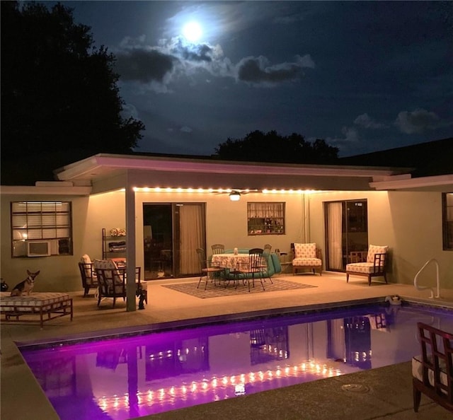 back house at night featuring a patio