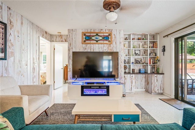 living room featuring wood walls, a textured ceiling, and ceiling fan