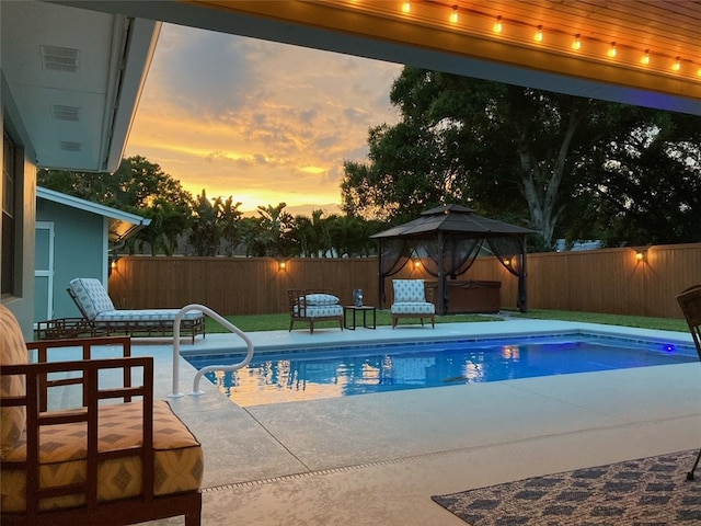 pool at dusk with a patio area and a gazebo