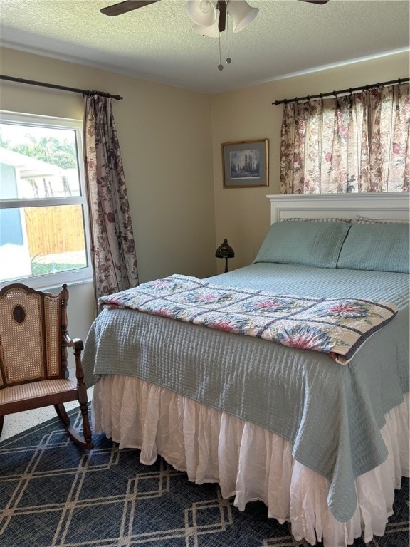 carpeted bedroom featuring ceiling fan and a textured ceiling