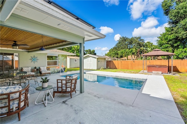 view of pool with a gazebo, a hot tub, ceiling fan, a patio, and a storage shed