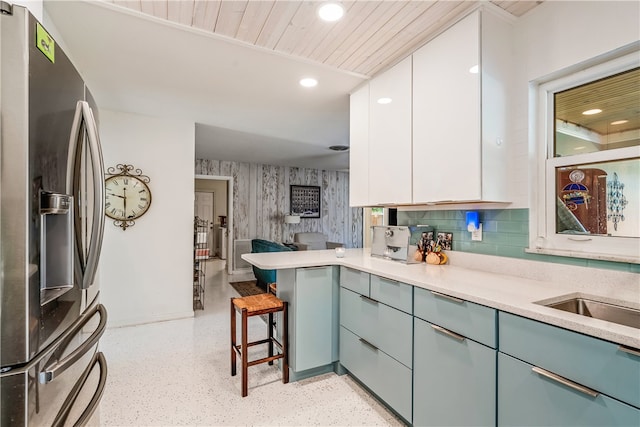 kitchen with a kitchen bar, wood ceiling, white cabinets, kitchen peninsula, and stainless steel fridge with ice dispenser