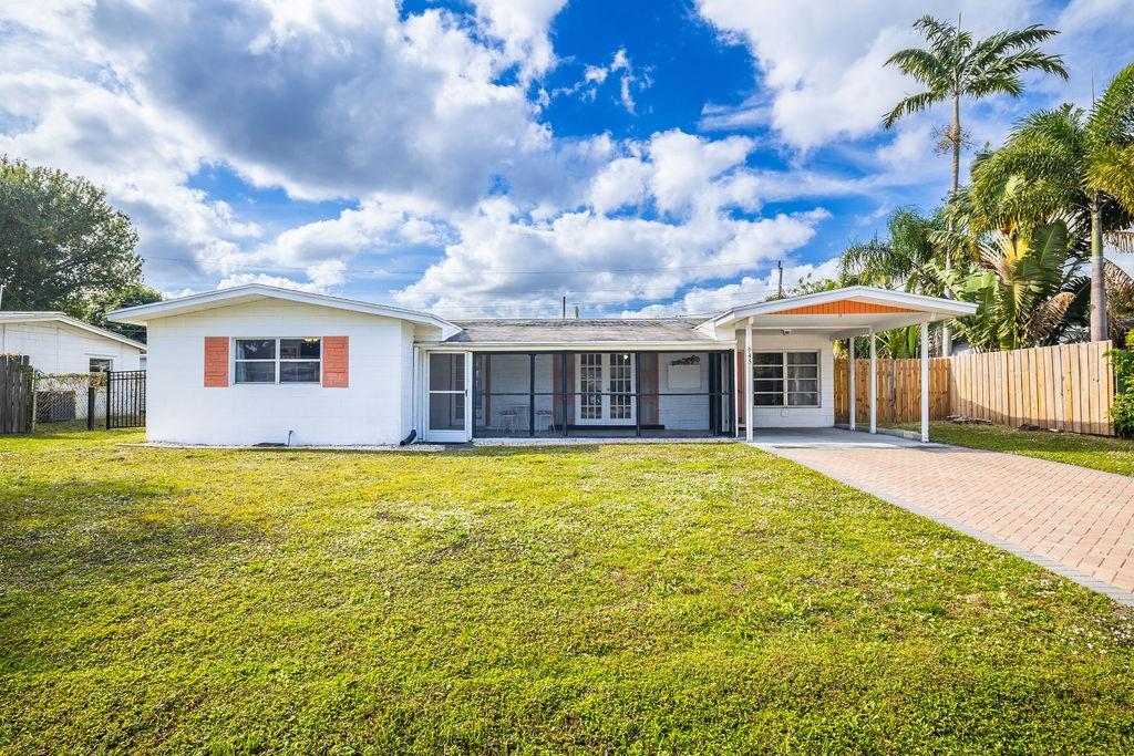 ranch-style house featuring a carport and a front lawn