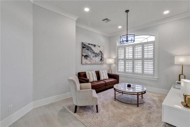 living room with a chandelier, light wood-type flooring, and crown molding