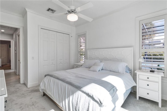 bedroom featuring ceiling fan, a closet, light carpet, and ornamental molding