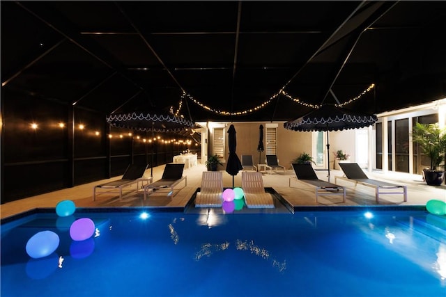 pool at night featuring a patio area