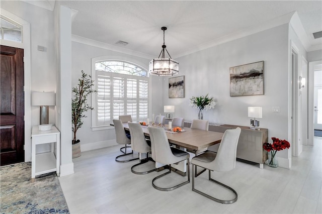 dining area with light hardwood / wood-style floors, a notable chandelier, and ornamental molding