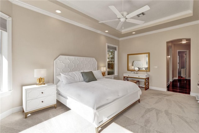 carpeted bedroom featuring multiple windows, a raised ceiling, ceiling fan, and ornamental molding