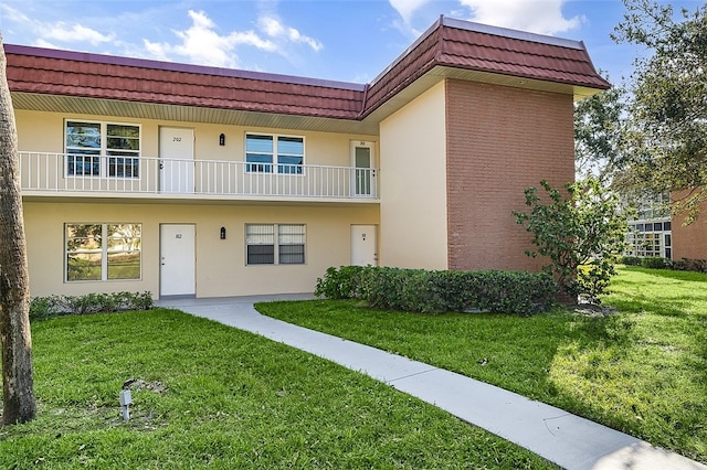 view of property with a balcony and a front yard