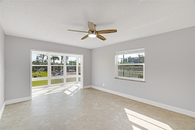 tiled empty room with a wealth of natural light, a textured ceiling, and ceiling fan