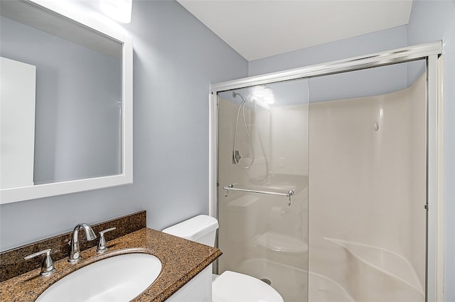 bathroom featuring toilet, vanity, and a shower with door