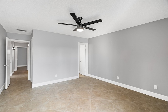 tiled empty room with ceiling fan and a textured ceiling