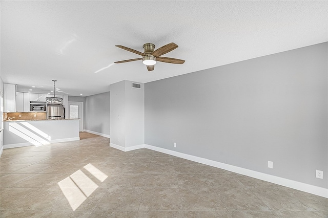 unfurnished living room with light tile patterned flooring, ceiling fan, and a textured ceiling