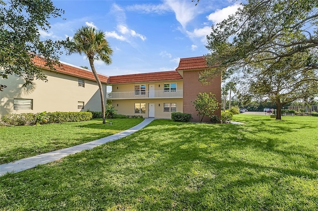 rear view of house featuring a lawn and a balcony