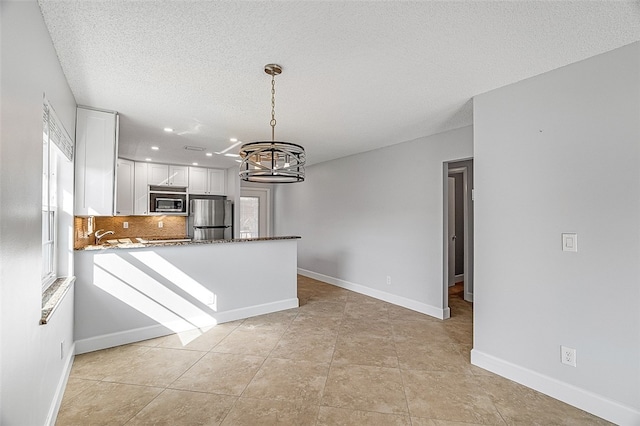 kitchen with stainless steel appliances, kitchen peninsula, a notable chandelier, white cabinets, and pendant lighting