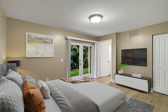 bedroom with a closet, a textured ceiling, and light hardwood / wood-style flooring