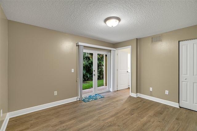 spare room featuring wood-type flooring and a textured ceiling