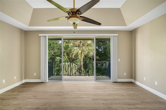 spare room with a tray ceiling and light wood-type flooring