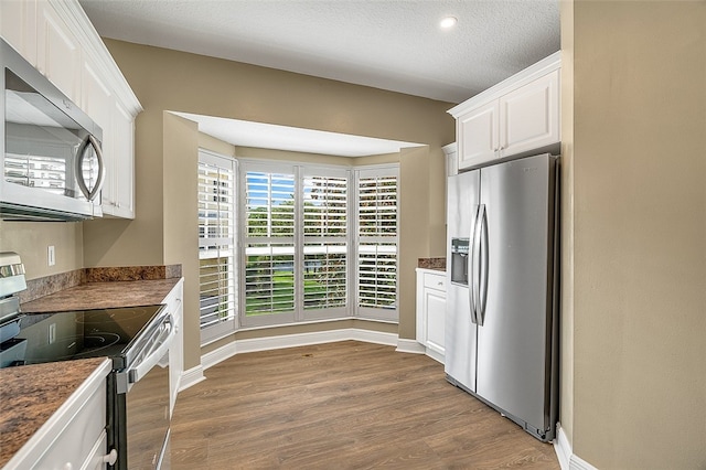 kitchen with white cabinets, appliances with stainless steel finishes, a textured ceiling, and light hardwood / wood-style flooring