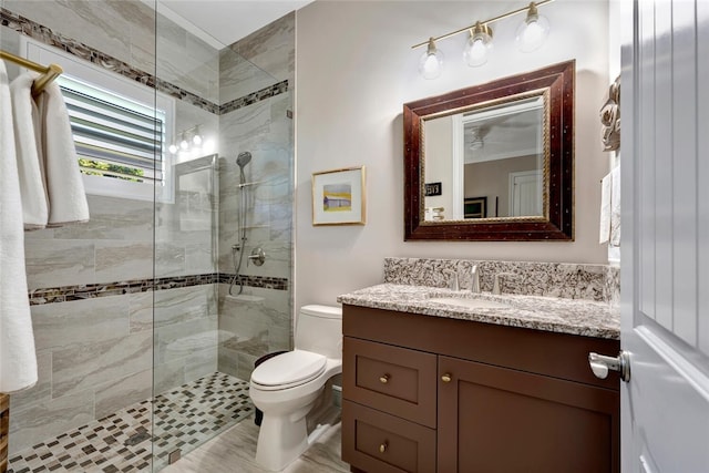 bathroom featuring crown molding, vanity, toilet, and a tile shower