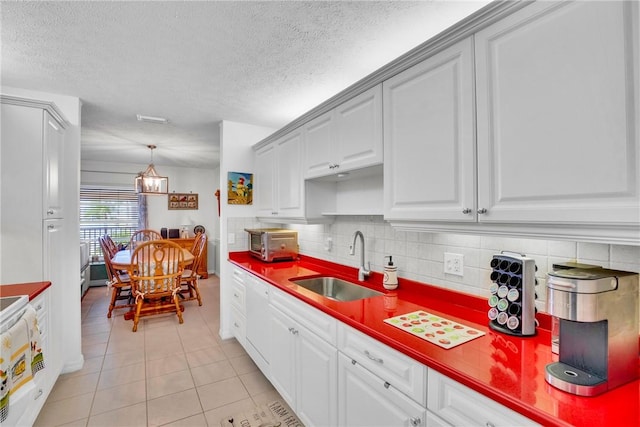 740 Lake Orchid Cir Unit 205, Vero Beach, FL 32962 - kitchen featuring a sink, light tile patterned floors, a textured ceiling, decorative backsplash, and white cabinetry