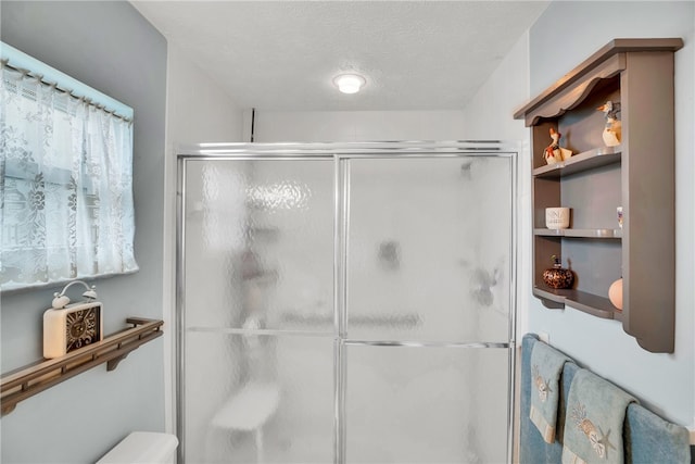 bathroom featuring a textured ceiling, a stall shower, and toilet