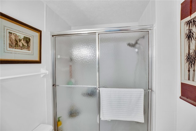 bathroom with a textured ceiling and a shower with door