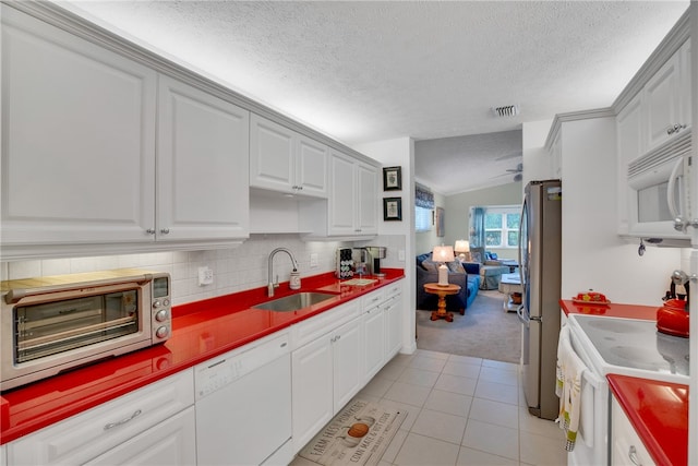 kitchen with sink, white appliances, light tile patterned floors, and a textured ceiling