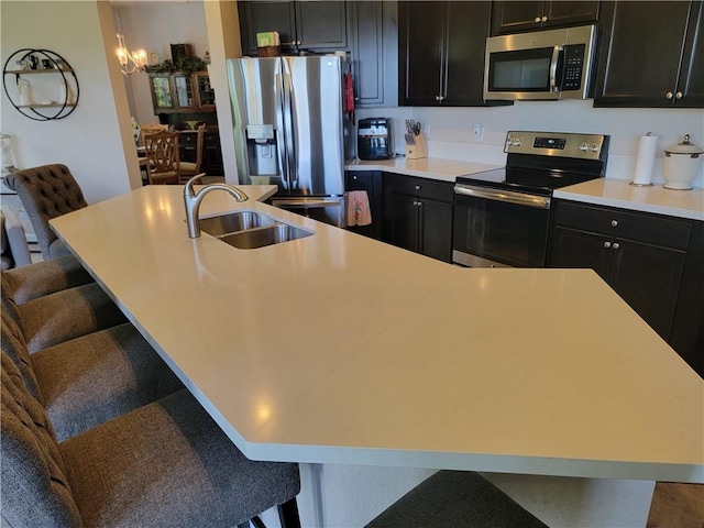 1808 Berkshire Cir SW, Vero Beach, FL 32968 - kitchen featuring appliances with stainless steel finishes, a kitchen island with sink, a kitchen breakfast bar, dark cabinetry, and light countertops