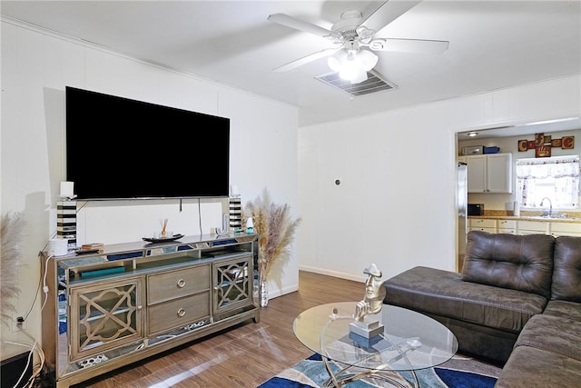 living room featuring hardwood / wood-style flooring, ceiling fan, and sink